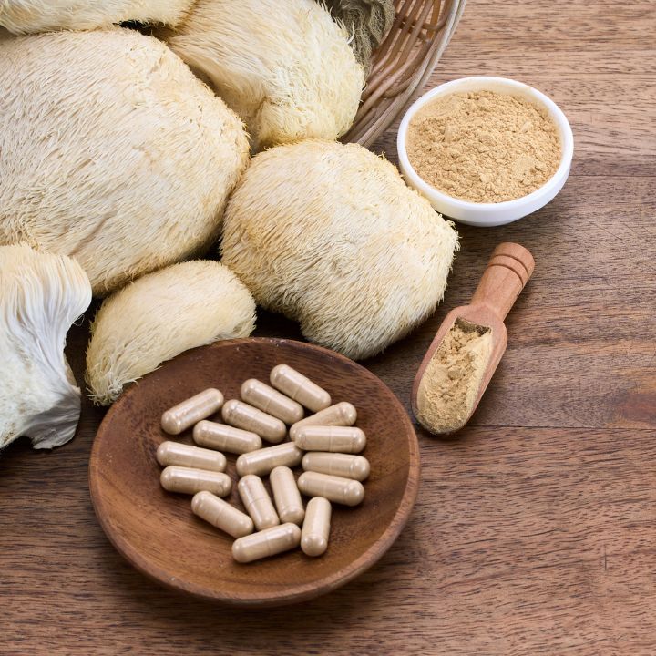 LION'S MANE Pilz getrocknet auf einem Tisch mit LION'S MANE Pulver Kapseln.