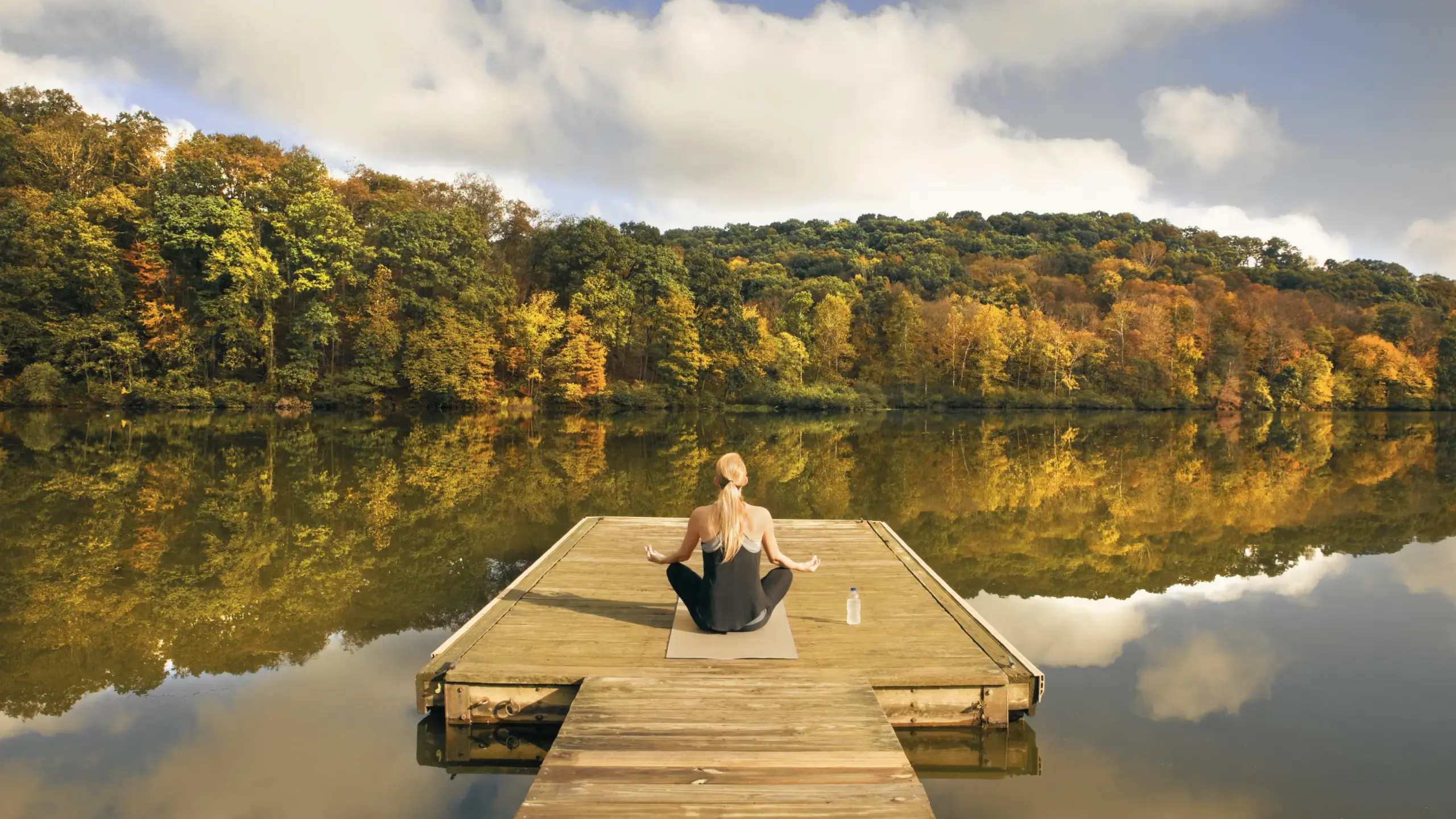 a woman sitting on a dock on a lake